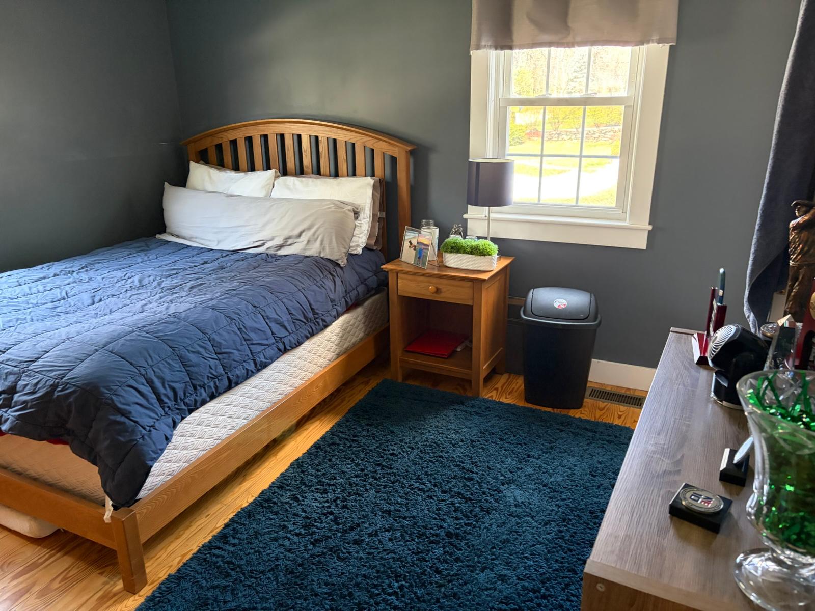 Neat bedroom with navy bedding and clean hardwood floor